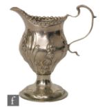A George III hallmarked silver pedestal cream jug with later embossed foliate decoration, height