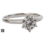An 18ct white gold diamond solitaire ring, brilliant cut claw set stones to plain shoulders,