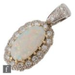An 18ct white gold opal and diamond pendant, central claw set oval opal, length 15mm within a