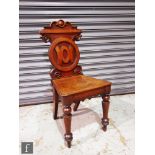 An early 20th Century oak elbow chair with slender spindle back over a dished saddle seat, raised to