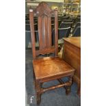 A 19th Century oak side or hall chair with high panel back with an acanthus carved top rail over