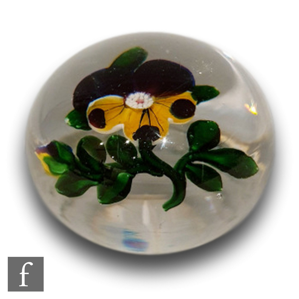 A 19th Century French Baccarat glass paperweight, internally decorated with a pansy and bud in