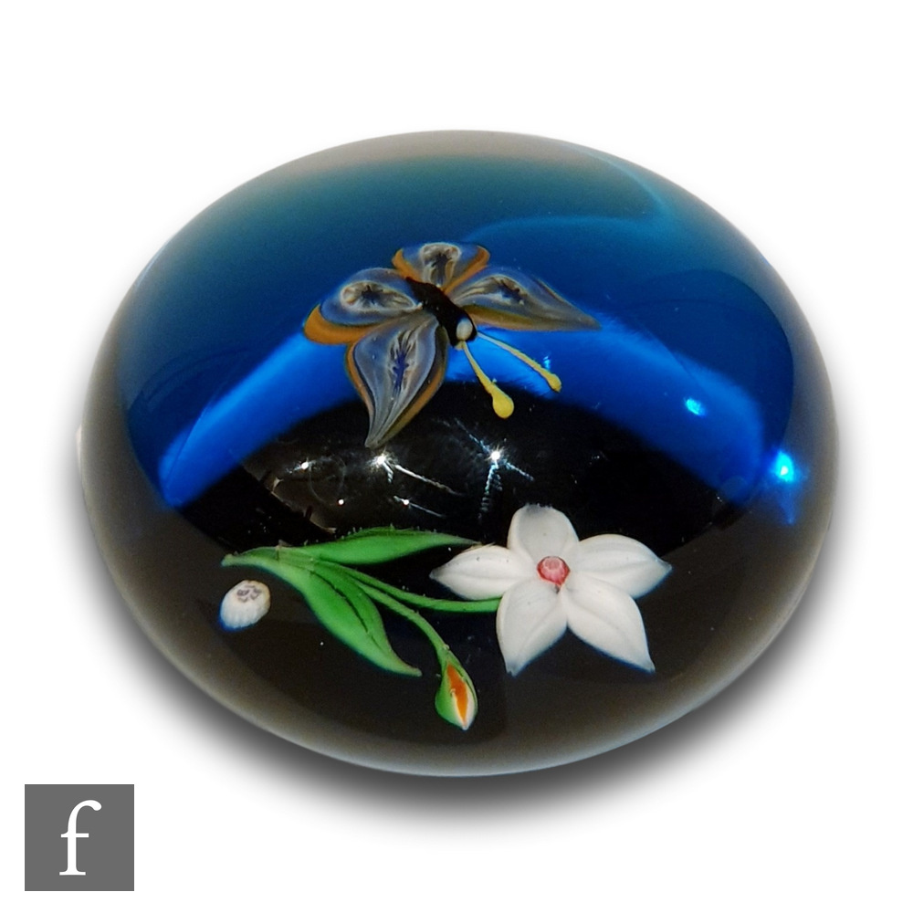A Baccarat glass paperweight internally decorated with a white flower and bud with a colourful