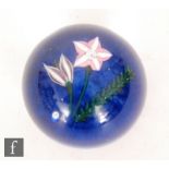 A 20th Century Scottish glass paperweight by John Deacons with a pink clematis, purple bud and