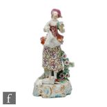 A late 18th to early 19th Century Derby type model of a flower seller, stood on a rococo scroll base