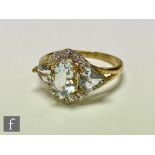 A 9ct aquamarine and diamond cluster ring, central oval aquamarine flanked by two further heart