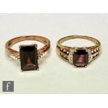 Two 9ct hallmarked garnet and diamond rings each with a central emerald cut, claw set garnet flanked