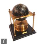 A late 20th Century black spherical world clock supported on a brass pillar frame, by the