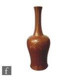 A Chinese iron-rust monochrome glazed bottle vase, the waisted vessel rising to a tapered shaft