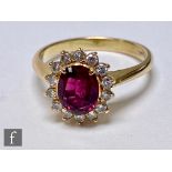 A 14ct ruby and diamond cluster ring, central oval ruby within a fourteen brilliant cut diamond