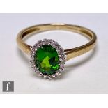 A 9ct hallmarked diopside and diamond cluster ring, central diopside within a diamond set border,
