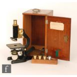 An early 20th Century black painted cast iron and brass fitted microscope with accessories in
