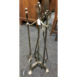 An Arts and Crafts wrought iron three-piece fireside companion set with whiplash terminals, complete