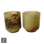 A pair of Chinese hardstone beakers of footed cylindrical form in green with tonal brown