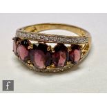 A 9ct hallmarked graduated five stone garnet ring, claw set stones within a diamond set border,