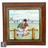 A framed 8in tile decorated with a tubelined Dutch scene with a lady and gentleman kissing whilst