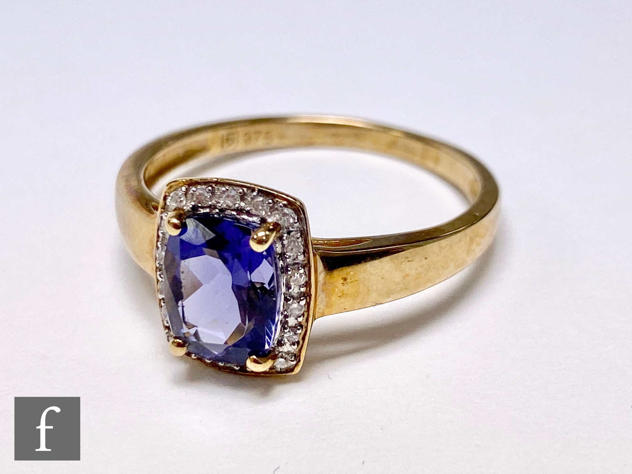 A 9ct hallmarked iolite and diamond cluster ring, central cushioned emerald cut claw set iolite