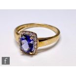 A 9ct hallmarked iolite and diamond cluster ring, central cushioned emerald cut claw set iolite