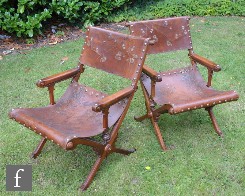 A pair of walnut framed open armchairs in the Aesthetic style, with chamfered X-shaped frames and