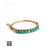 A 9ct rose gold turquoise and diamond hinged bangle with nine graduated turquoise spaced by pairs of