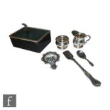 A small parcel lot of hallmarked silver, a cheese scoop, a cream and sugar, a tea strainer, a