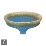 A Ruskin Pottery tri-footed bowl decorated with a yellow green dribble glaze running from the rim to