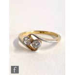 An early 20th Century 18ct two stone cross over ring, millgrain set diamonds to platinum