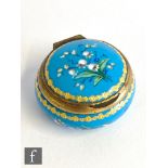 A 19th Century circular blue and gilt enamel patch box decorated with lily of the valley on a blue