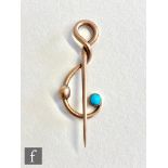 An early 20th Century 9ct lapel pin modelled as a treble clef with a single set turquoise, length