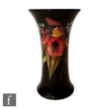 A Moorcroft trumpet vase decorated in the Frilled Orchid pattern with a band of flowers against a