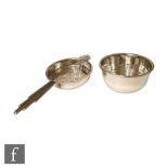 An Art Deco hallmarked silver tea strainer and drip bowl terminating in elongated fan handle, length