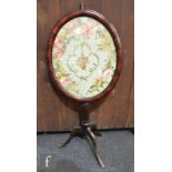 A Victorian pole screen, the oval framed panel with needlework floral study and with a tripod