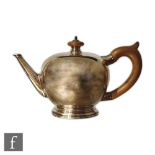 An American Sterling silver teapot of plain circular form with wooden scroll handle and button
