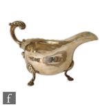 A hallmarked silver sauce boat of plain form raised on three stepped pad feet and terminating in