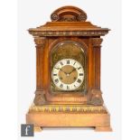 A Victorian walnut mantle clock with eight striking movement by Junghans, the arched dial enclosed