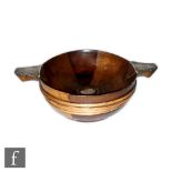 A turned wooden and white metal quaich, the segmented wooden bowl with central silver roundel