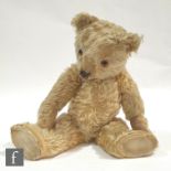 A 1930s and 1940s English blond plush teddy bear with black stitched nose, later eyes and pads,