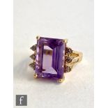 A 14ct amethyst and diamond ring, central emerald cut amethyst length 14mm, flanked by three