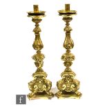 A pair of late 19th Century pressed gilt brass Italianate alter candlesticks on scroll feet and