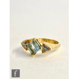 An 18ct hallmarked aquamarine and diamond three stone ring, central off set square cut aquamarine