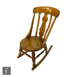 A light walnut rocking chair with bar back over a pierced splat oval seat, turned legs and