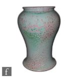 Ruskin Pottery - A high fired vase of waisted form with a flared foot, the whole decorated in a