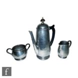 Liberty & Co - An English Pewter coffee pot, milk jug and sugar bowl, all with a planished effect,