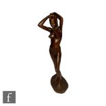 A contemporary cast bronze figure of a standing female nude with her hands raised above her head,