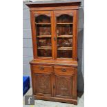 A Victorian carved mahogany bookcase enclosed by a pair of glazed doors below a fluted cornice