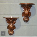 A pair of late 19th Century Black Forest carved oak wall bracket shelves, each with a demi-lune
