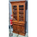 A Victorian mahogany bookcase enclosed by a pair of arched glazed doors below a fluted cornice