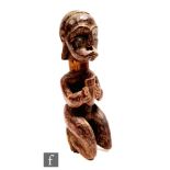 An African tribal figure, carved male figure kneeling holding an offering cup, with stylised