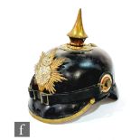 A World War One German pickelhaube in black leather mounted with divisional badge, brass edged peak,