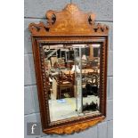 An early 20th Century Art Nouveau style marquetry inlaid wall mirror, the carved pediment over